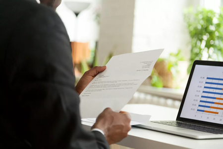 GettyImages-916520012-8c6356fb1ad84d05a24515cfb50412dc image of a person looking at their resume and laptop