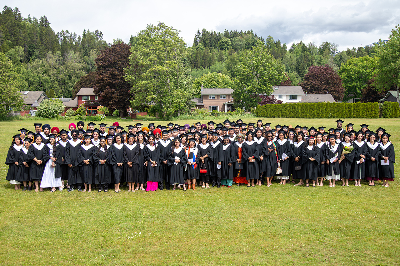 The CMTN Terrace Class of 2026 poses on a lawn in their graduation caps and gowns. There are houses and trees in the background.