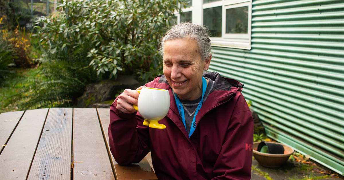 Emilia sips her coffee on a picnic table at CMTN's Prince Rupert campus
