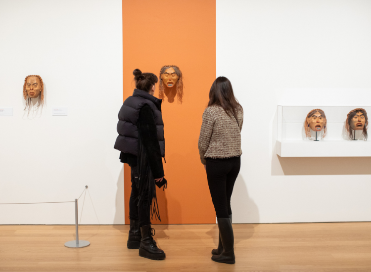 Attendees study a mask carved by Freda Diesing at the exhibition opening.