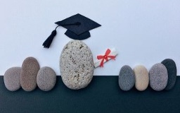 illustrative image of stones as people, the central one is wearing a graduation cap and carrying a diploma